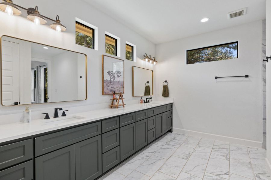 Full bath featuring double vanity, light marble finish flooring, recessed lighting, and a shower