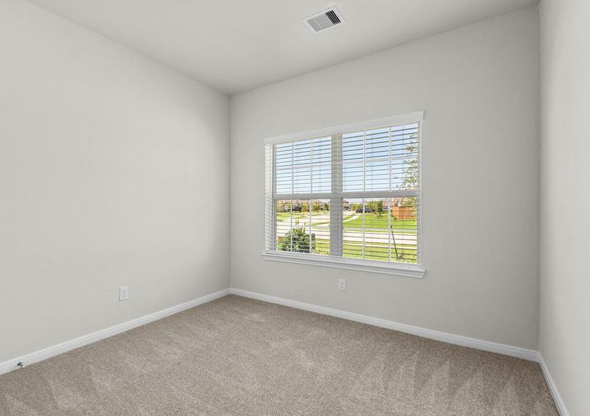 A spacious secondary bedroom with a window overlooking the front yard