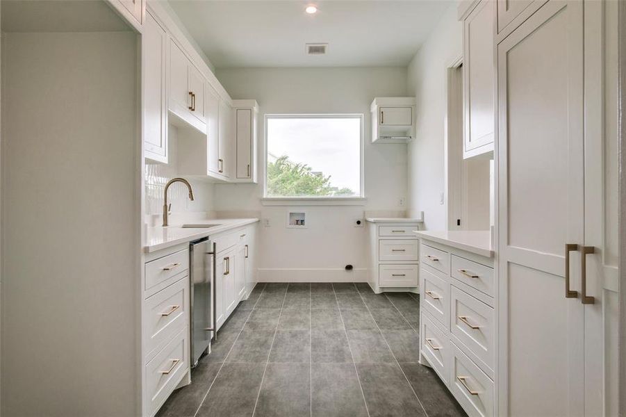Kitchen with light countertops, visible vents, white cabinetry, and a sink