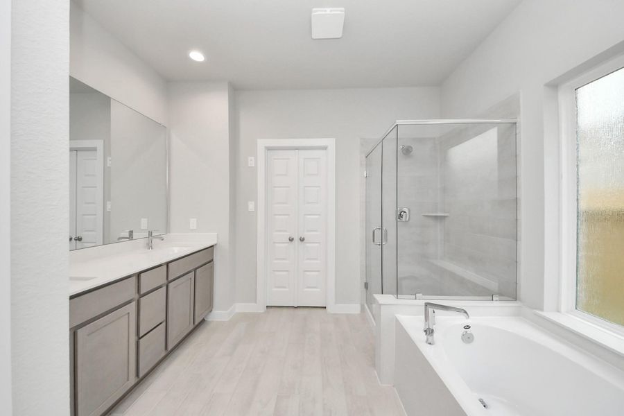 This additional view of the primary bath features a walk-in shower with the tile surround and separate garden tub perfect for soaking after a long day. Sample photo of completed home with similar floor plan. Actual colors and selections may vary.