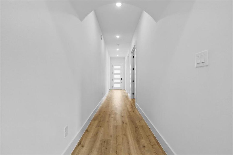 Hallway with recessed lighting, arched walkways, light wood-style floors, and baseboards