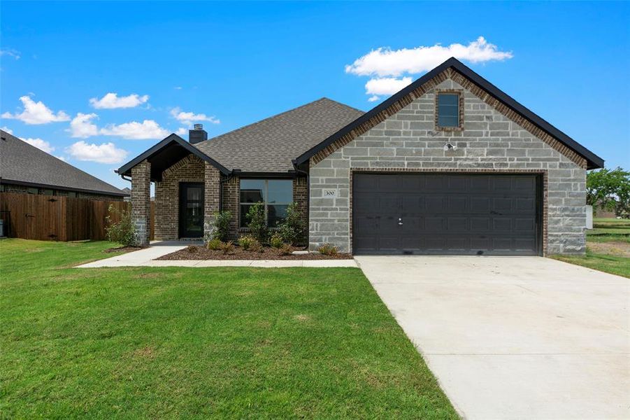 View of front facade featuring concrete driveway, an attached garage, a chimney, brick siding, and roof with shingles