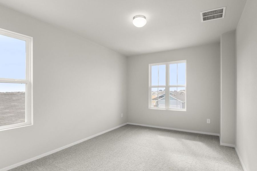 Image of a primary bedroom with light grey walls, tan carpeting and a window