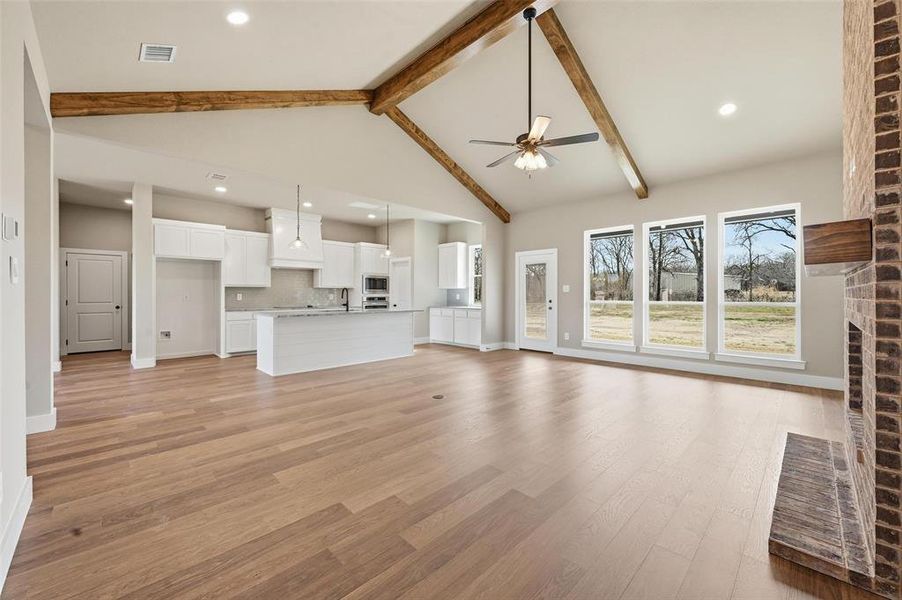 Unfurnished living room with recessed lighting, light wood-style flooring, a ceiling fan, a brick fireplace, and lofted ceiling