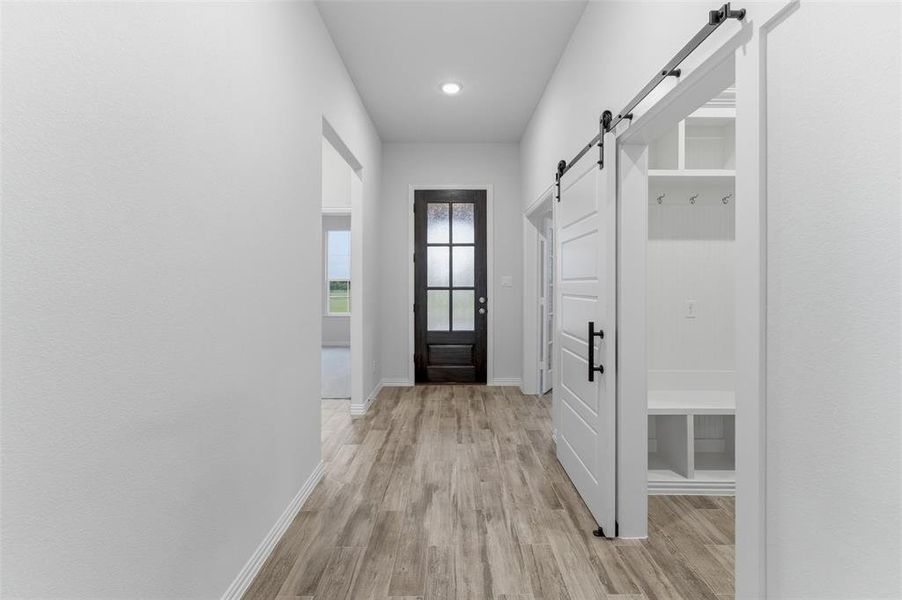 Entryway featuring wood-finish flooring, a dark-paneled door with frosted glass, and recessed lighting