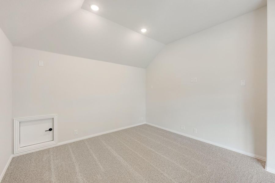 Empty room with vaulted ceiling, carpet flooring, recessed lights, and small access door on wall Empty room with vaulted ceiling, carpet flooring, recessed lights, and small access door on wall