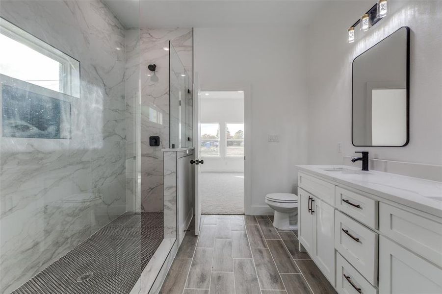 Bathroom with a tile shower, toilet, and a healthy amount of sunlight