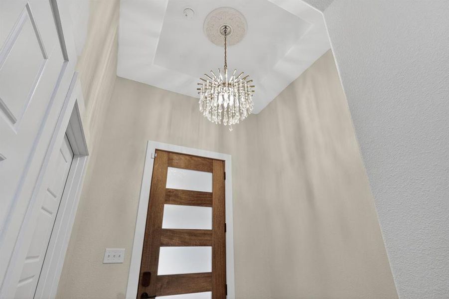 Picture of chandelier and entrance hall with semi gloss painting and custom paint color throughout the home brings charm and character to the unique designed home.