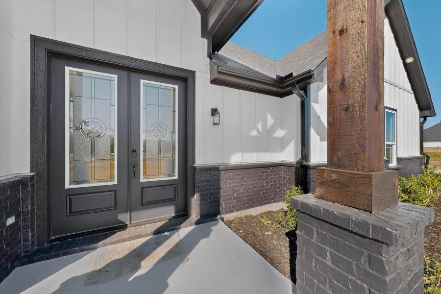 Doorway to property featuring french doors, board and batten siding, and brick siding Doorway to property featuring french doors, board and batten siding, and brick siding