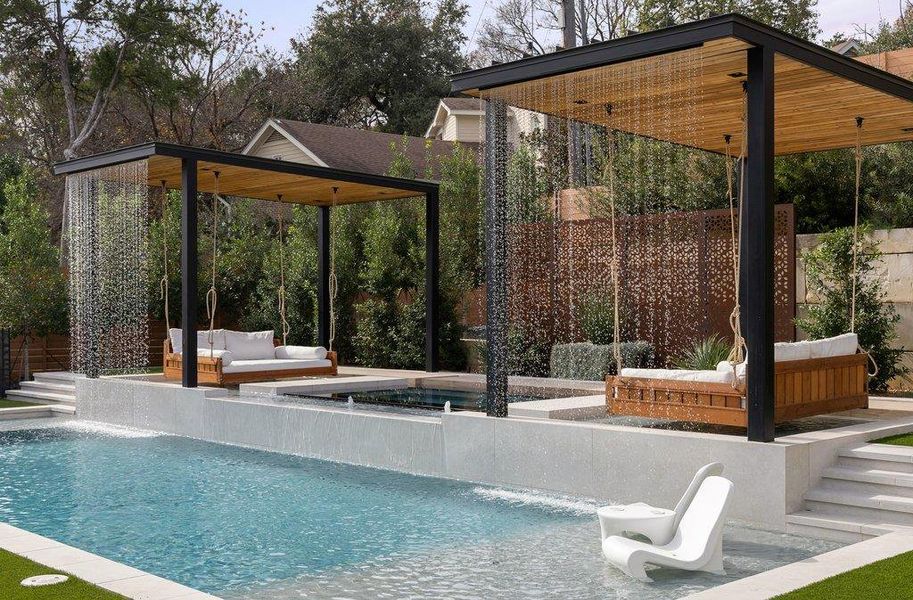 Outdoor aquatic area featuring a large swimming pool with a broad water wall