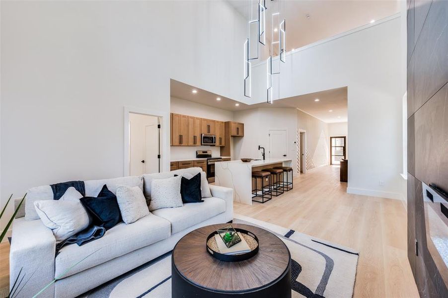 Living room featuring sink, light hardwood / wood-style floors, and a high ceiling