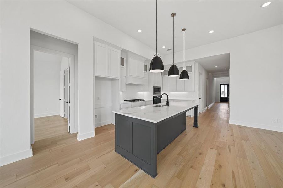 Kitchen featuring white cabinets, light wood-style floors, recessed lighting, pendant lighting, and a center island with sink Kitchen featuring white cabinets, light wood-style floors, recessed lighting, pendant lighting, and a center island with sink