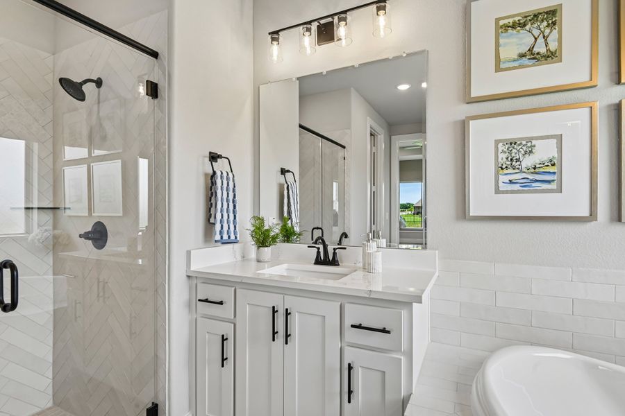 Bathroom with white vanity, quartz countertop, glass shower, and subway tile walls