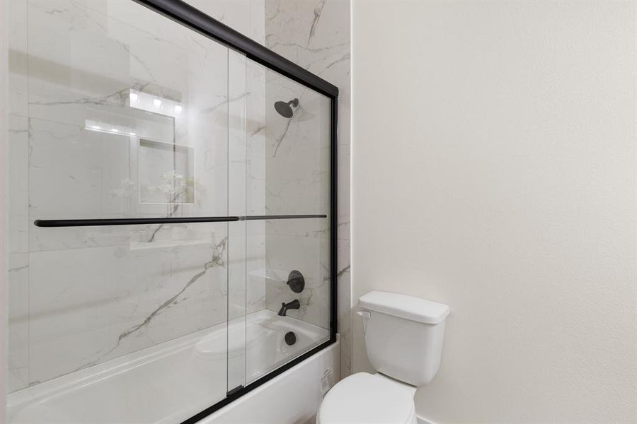 Bathroom with combined bath / shower with glass door and toilet