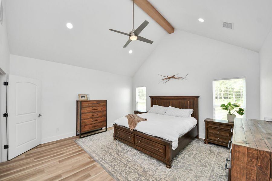 Spacious bedroom with vaulted ceiling, featuring elegant wooden furniture and abundant natural light from large windows, creating a warm and inviting atmosphere. Spacious bedroom with vaulted ceiling, featuring elegant wooden furniture and abundant natural light from large windows, creating a warm and inviting atmosphere.