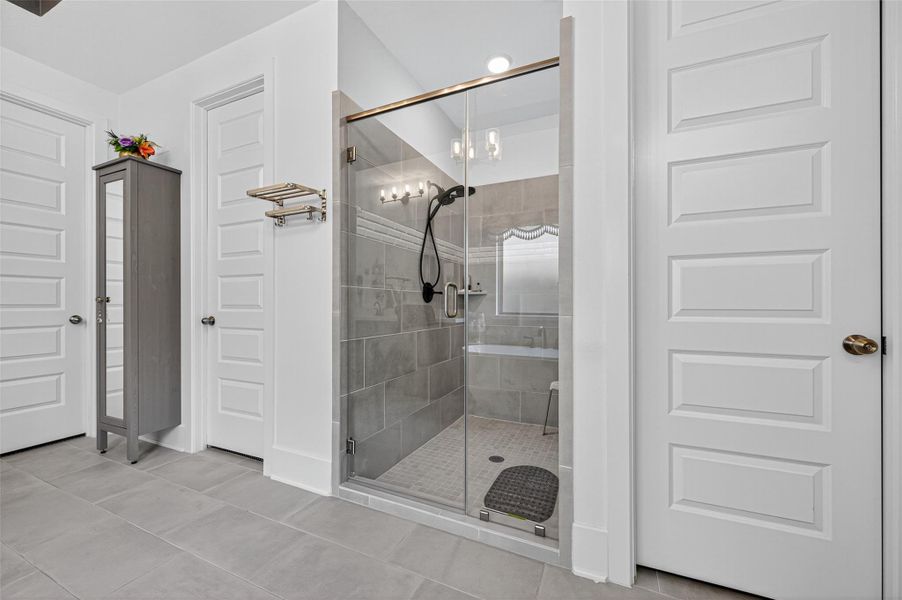 This modern bathroom features a spacious glass-enclosed shower with sleek gray tiles, dual showerheads, and ample lighting. The room includes two white paneled doors, a tall cabinet for storage, and neutral-colored floor tiles for a clean, contemporary look. This modern bathroom features a spacious glass-enclosed shower with sleek gray tiles, dual showerheads, and ample lighting. The room includes two white paneled doors, a tall cabinet for storage, and neutral-colored floor tiles for a clean, contemporary look.
