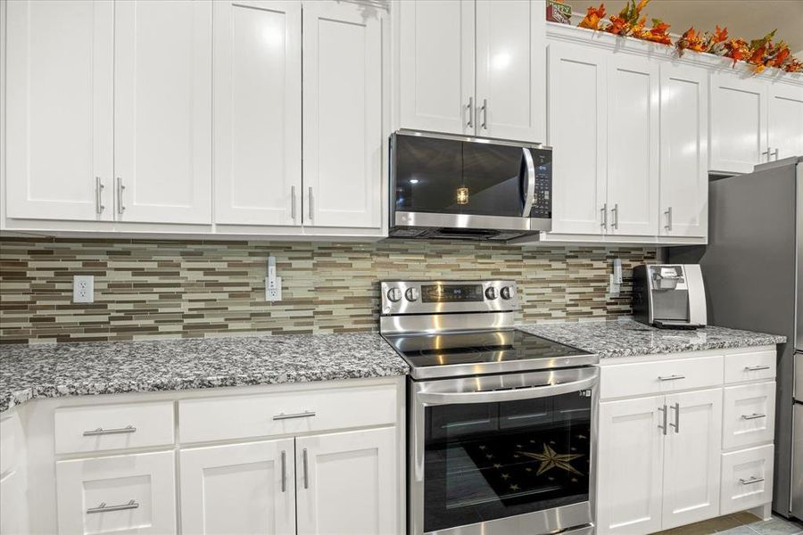 Kitchen featuring stainless steel appliances and white cabinets Kitchen featuring stainless steel appliances and white cabinets
