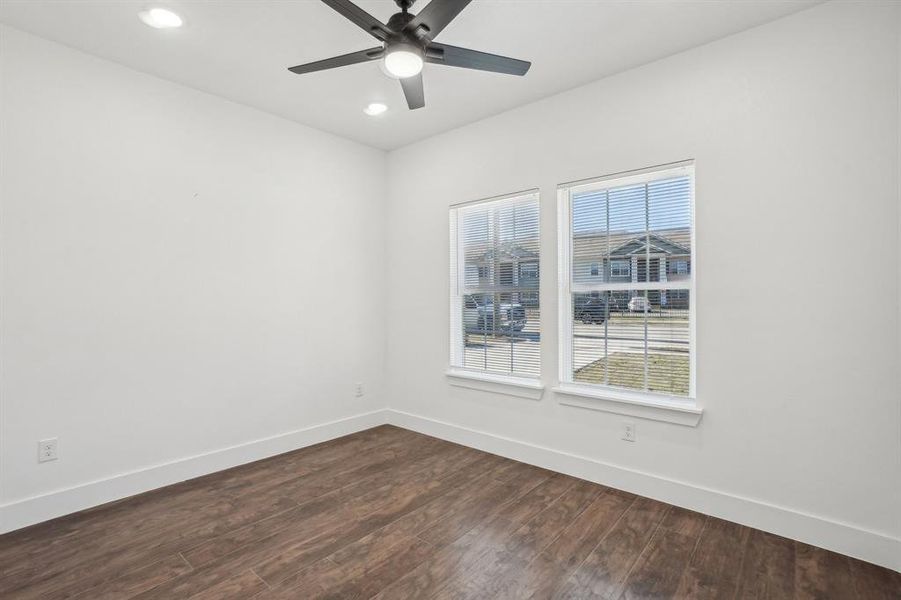 Front bedroom 1 with ceiling fan, dark wood-type flooring, and a healthy amount of sunlight