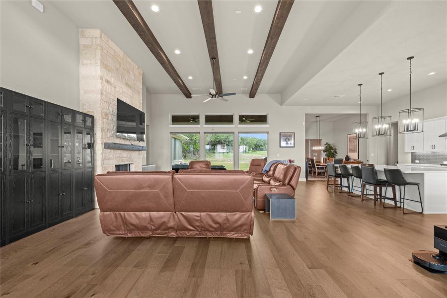 A spacious great room showcases soaring beamed ceilings, wide plank wood flooring, and a stone fireplace. A spacious great room showcases soaring beamed ceilings, wide plank wood flooring, and a stone fireplace.