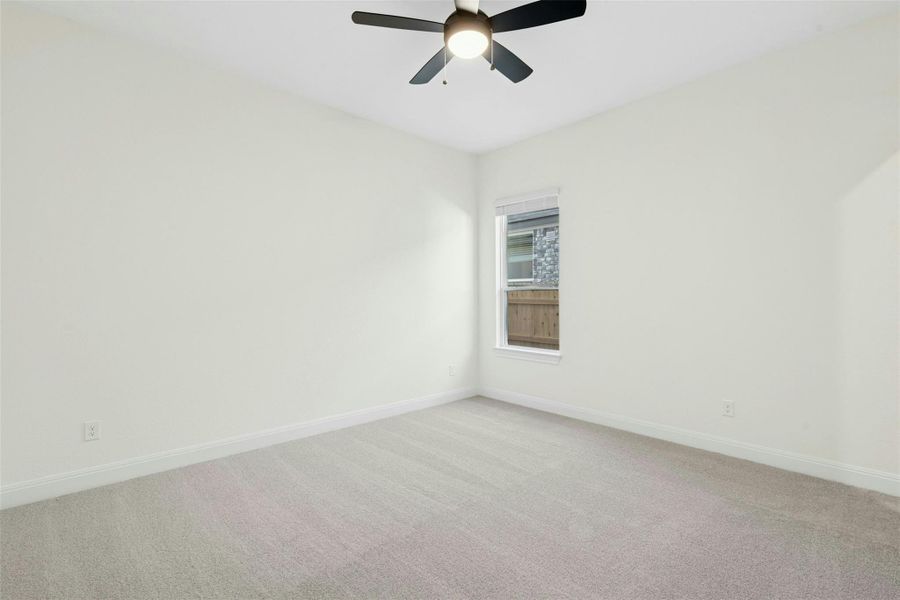 Empty room with light colored carpet and ceiling fan