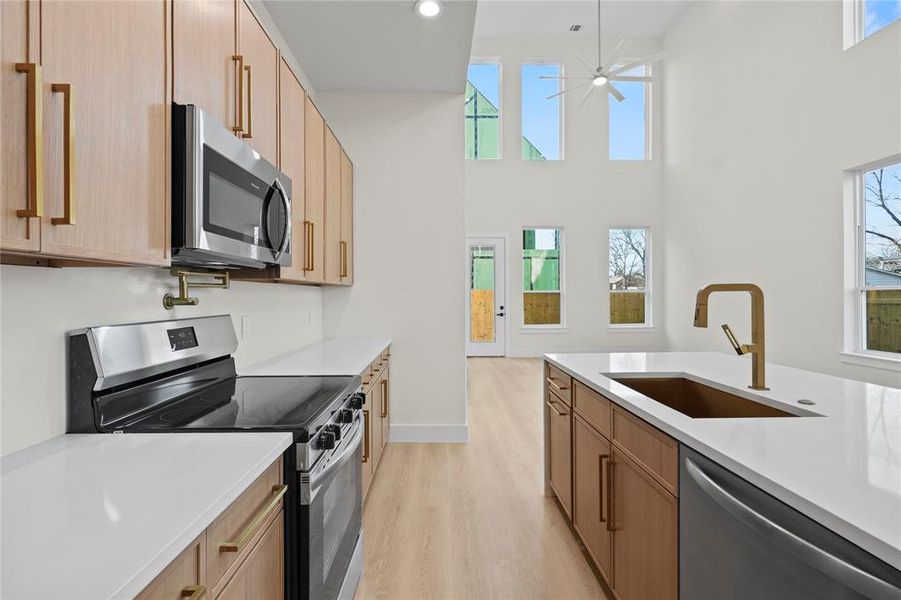 Kitchen with light countertops, appliances with stainless steel finishes, a sink, and pendant lighting