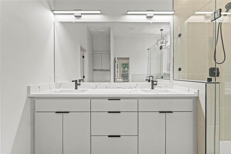 Full bath with double vanity and a shower stall