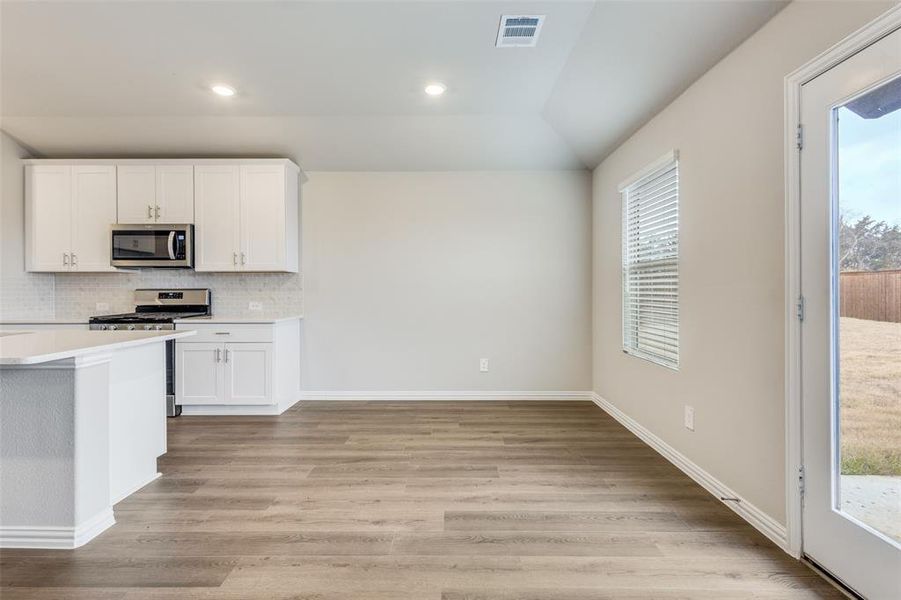 Kitchen featuring plenty of natural light, tasteful backsplash, white cabinetry, recessed lighting, and lofted ceiling