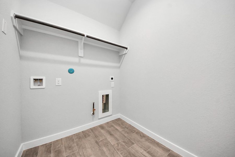 A perfect blend of functionality and comfort. Capture the essence of easy living with a first-floor laundry room, thoughtfully equipped with shelving for effortless organization. Both electric and gas connections available. Sample photo of completed home with similar floor plan. Actual colors and selections may vary.