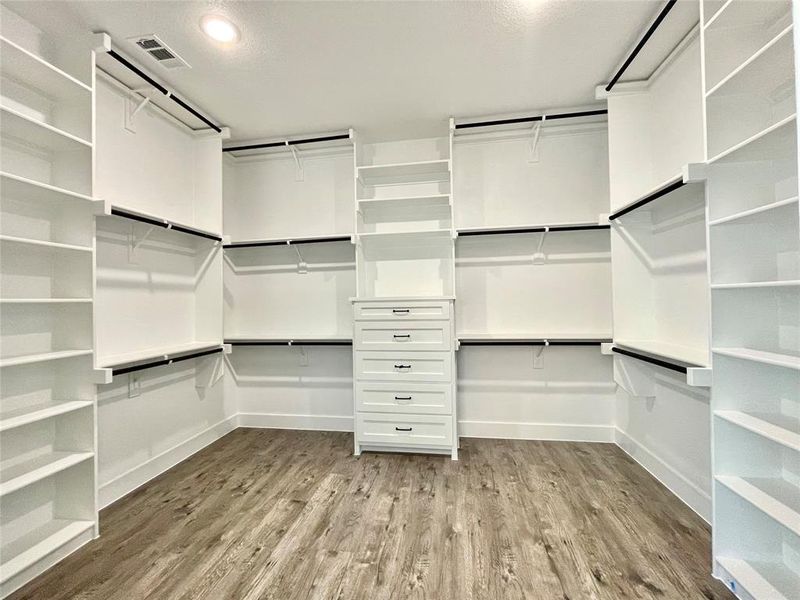 Walk in closet featuring wood finished floors and visible vents Walk in closet featuring wood finished floors and visible vents