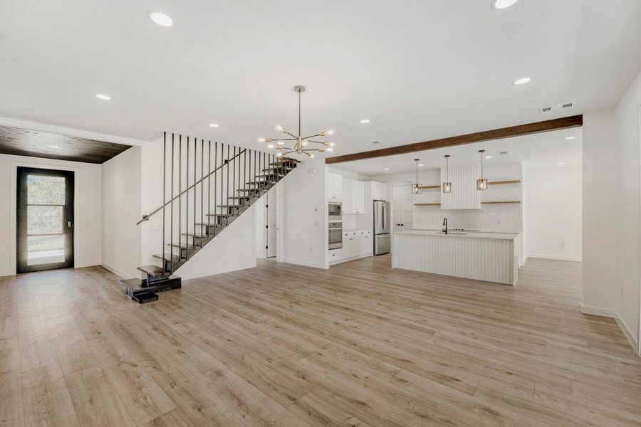 Unfurnished living room with a chandelier and light wood finished floors
