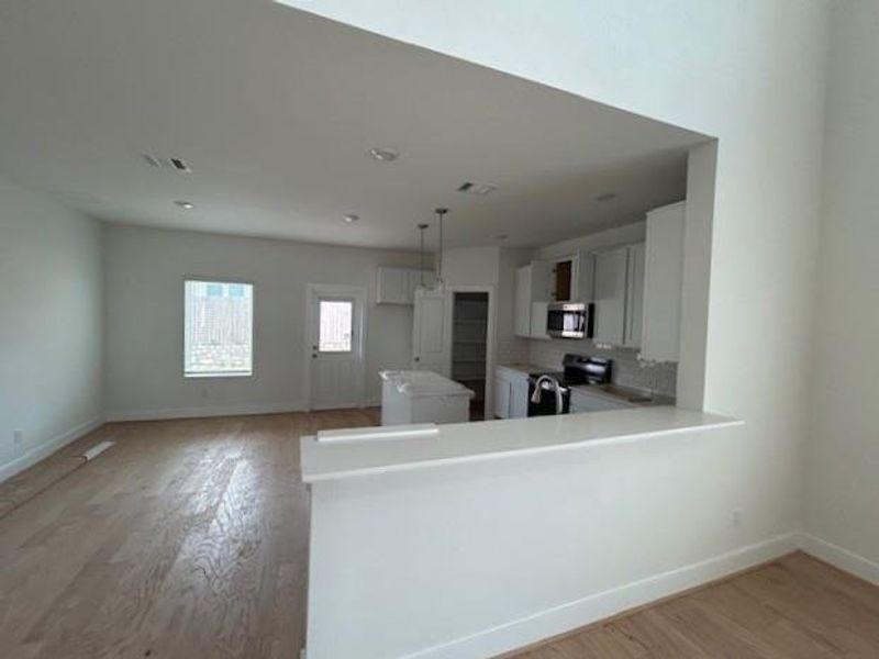 Kitchen featuring white cabinets, appliances with stainless steel finishes, light wood-style flooring, and light countertops