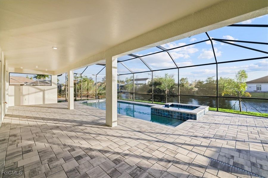 View of pool featuring a sunroom, a water view, glass enclosure, a patio, and a pool with connected hot tub