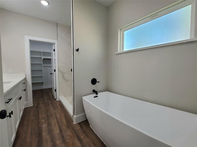 Primary Bathroom featuring hardwood / wood-style floors, vanity, and shower with separate bathtub