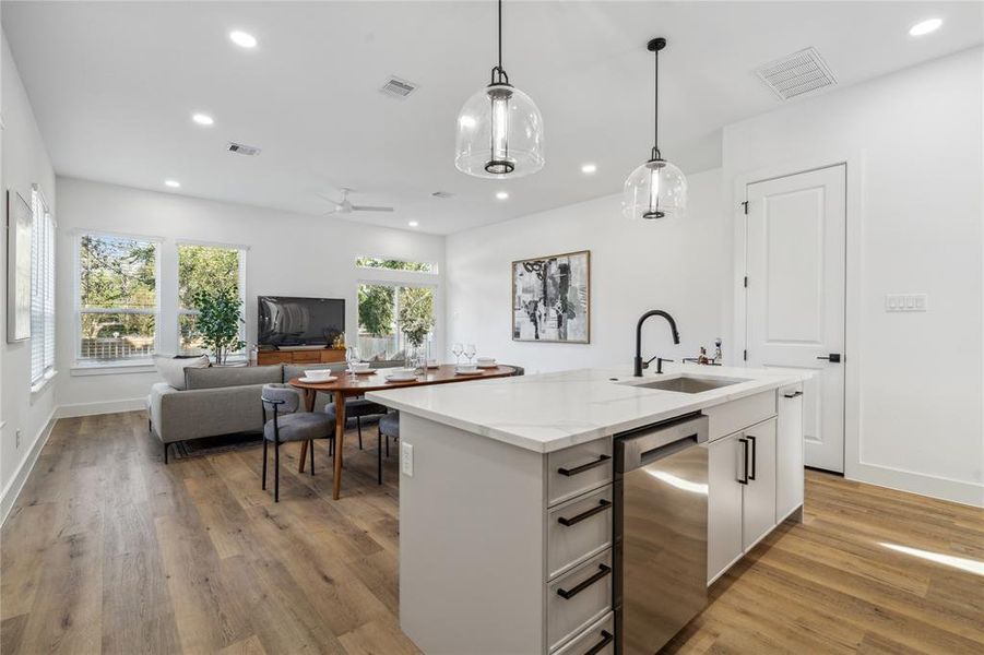 Stylish open-plan living and dining space featuring a modern kitchen island with quartz countertops, chic pendant lighting, and floor-to-ceiling windows that frame serene outdoor views.