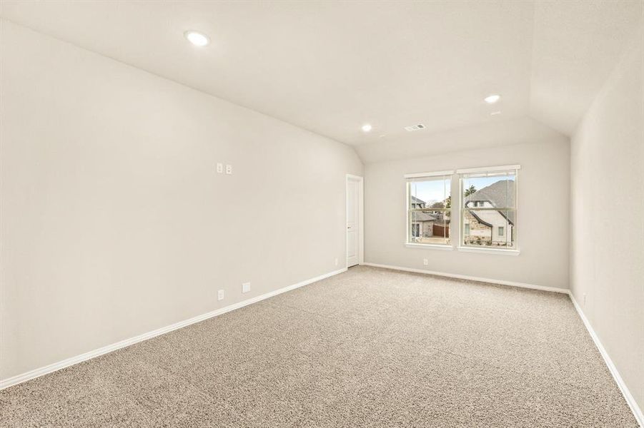 Carpeted empty room featuring vaulted ceiling and recessed lighting
