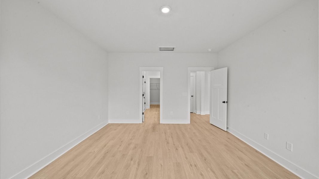 Superior design meets vibrant comfort in this primary suite with hardwood floors and walk-in closet