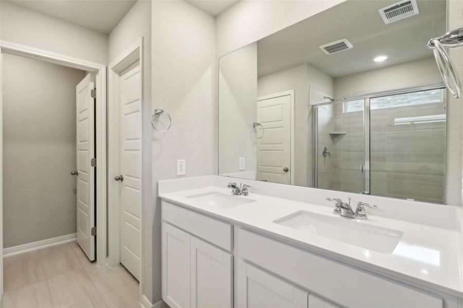 Bathroom featuring a shower stall, double vanity, baseboards, and recessed lighting Bathroom featuring a shower stall, double vanity, baseboards, and recessed lighting