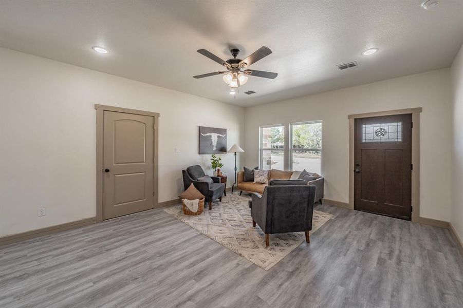 Living area with light wood-type flooring, a ceiling fan, and recessed lighting