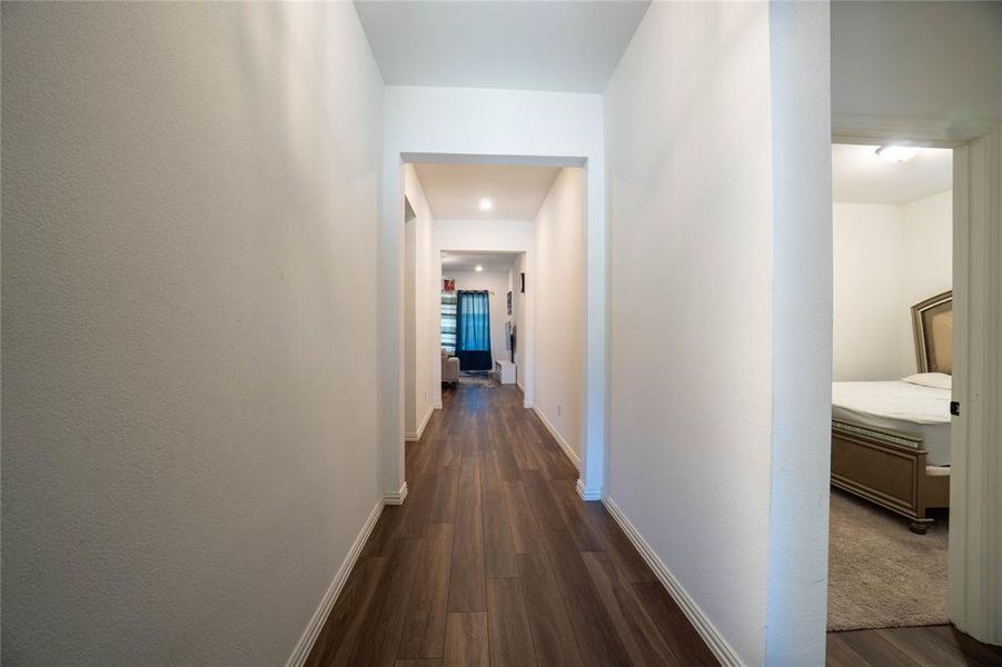 Hallway featuring wood-finish flooring, recessed lighting, white baseboards, and neutral wall finishes