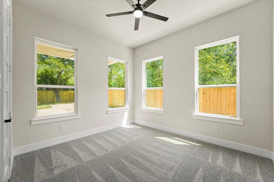 Carpeted empty room with healthy amount of natural light and a ceiling fan Carpeted empty room with healthy amount of natural light and a ceiling fan