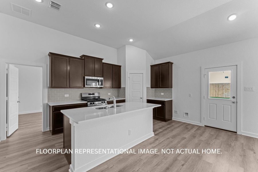A well-appointed kitchen features rich cabinetry, stainless steel appliances, and a central island with a sink, all set against durable flooring.