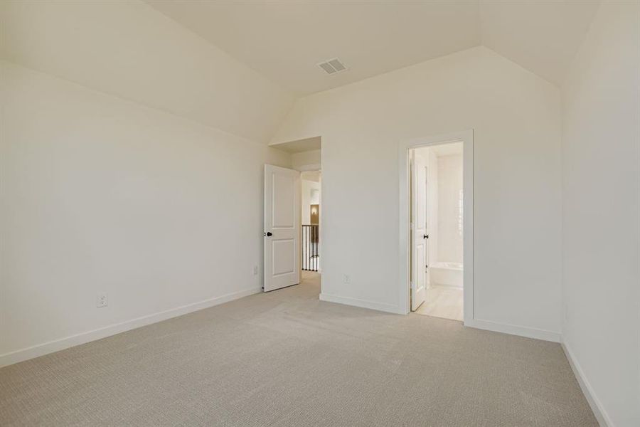 Unfurnished bedroom with carpet flooring, vaulted ceiling, and connected bathroom