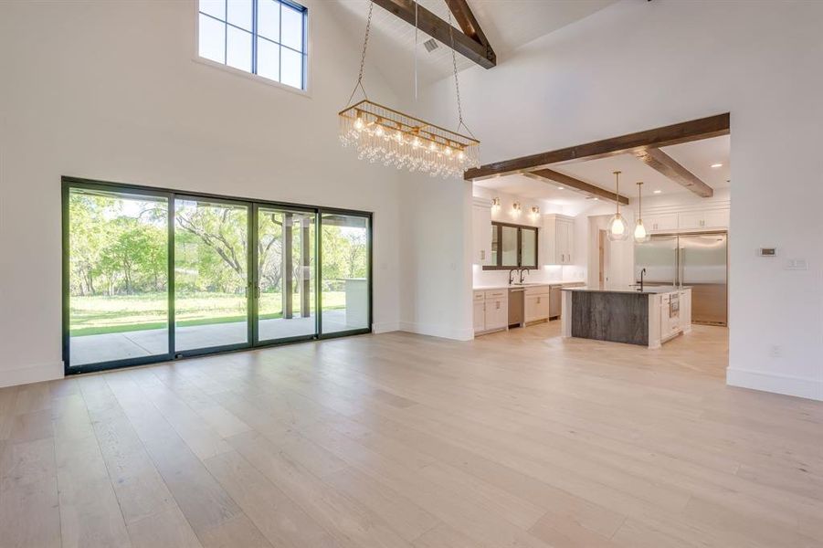 Unfurnished living room featuring hanging lights and light wood-style floors
