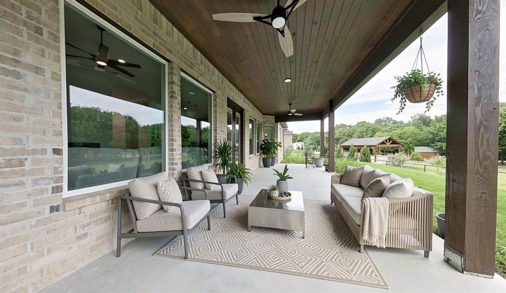 Expansive covered patio featuring a wood-plank ceiling, concrete flooring, and substantial structural columns Expansive covered patio featuring a wood-plank ceiling, concrete flooring, and substantial structural columns