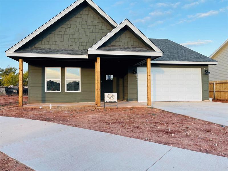View of front of property featuring roof with shingles, driveway, a garage, and a porch