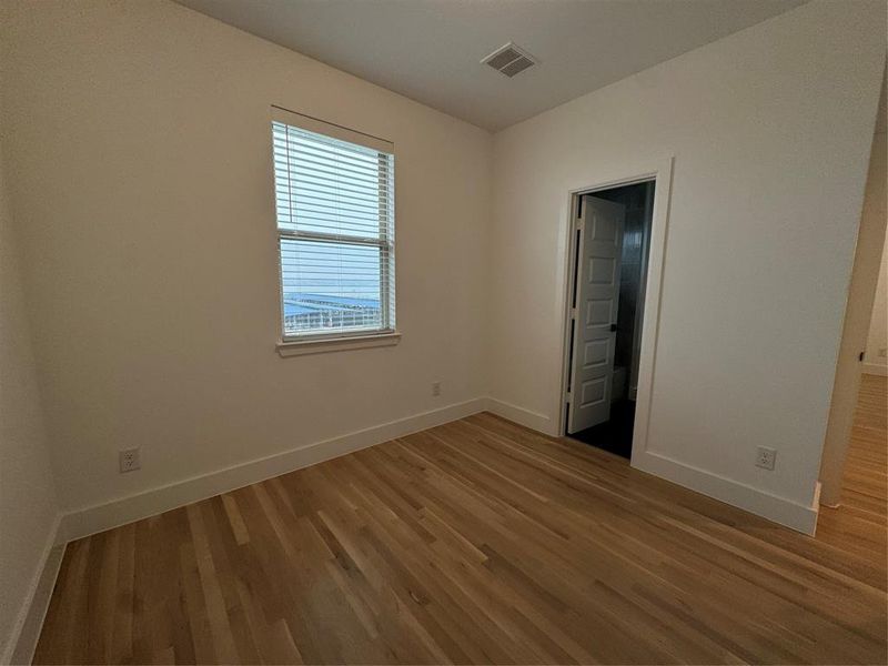 Unfurnished bedroom with visible vents, baseboards, and wood finished floors