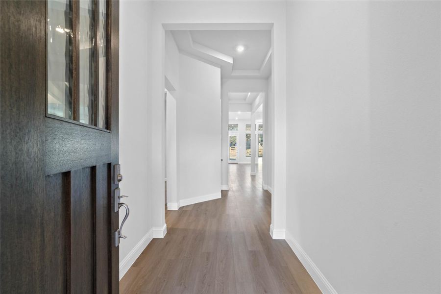 Step into a light-filled foyer where crisp white walls and soaring ceilings create an immediate sense of grandeur. The architectural tray ceiling adds a sophisticated touch of depth, drawing the eye upward and setting an elegant tone for the rest of the home. Step into a light-filled foyer where crisp white walls and soaring ceilings create an immediate sense of grandeur. The architectural tray ceiling adds a sophisticated touch of depth, drawing the eye upward and setting an elegant tone for the rest of the home.