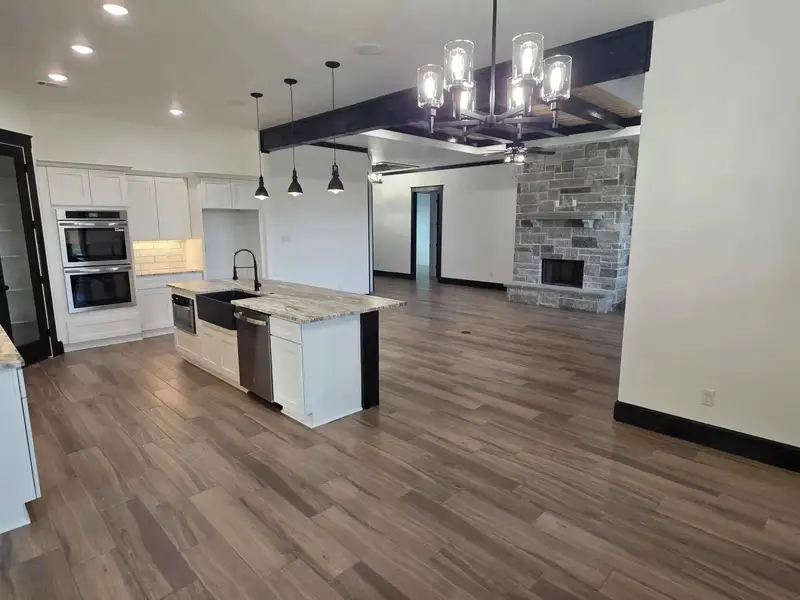 Kitchen with white cabinets, open floor plan, beamed ceiling, a fireplace, and stainless steel appliances Kitchen with white cabinets, open floor plan, beamed ceiling, a fireplace, and stainless steel appliances