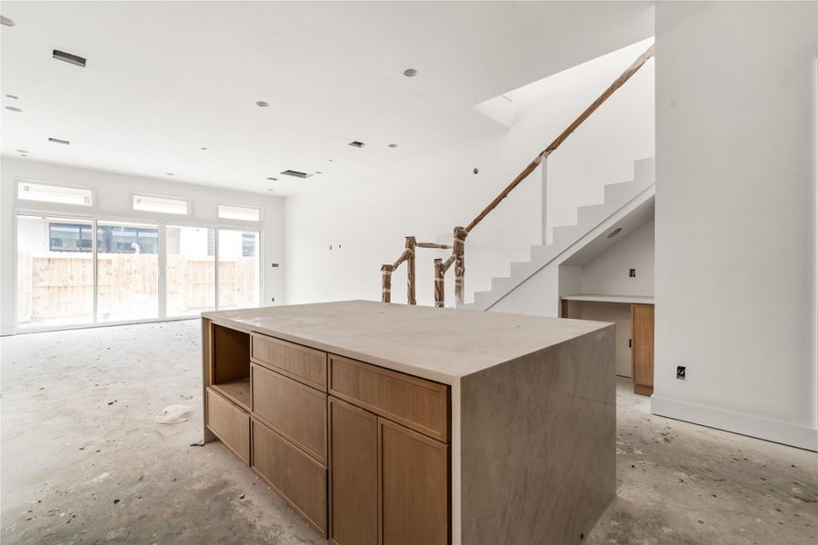 This home's kitchen comes with Taj Mahal counters, oversized island with storage on both sides, white oak slim shaker cabinetry, luxury Bosch appliances, Delta champagne bronze fixtures, and white oak wood flooring.