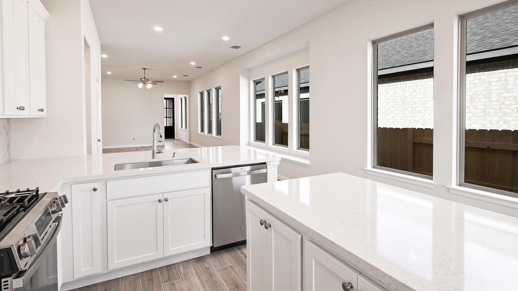 Kitchen featuring white cabinets, light stone countertops, recessed lighting, appliances with stainless steel finishes, and light wood-style floors